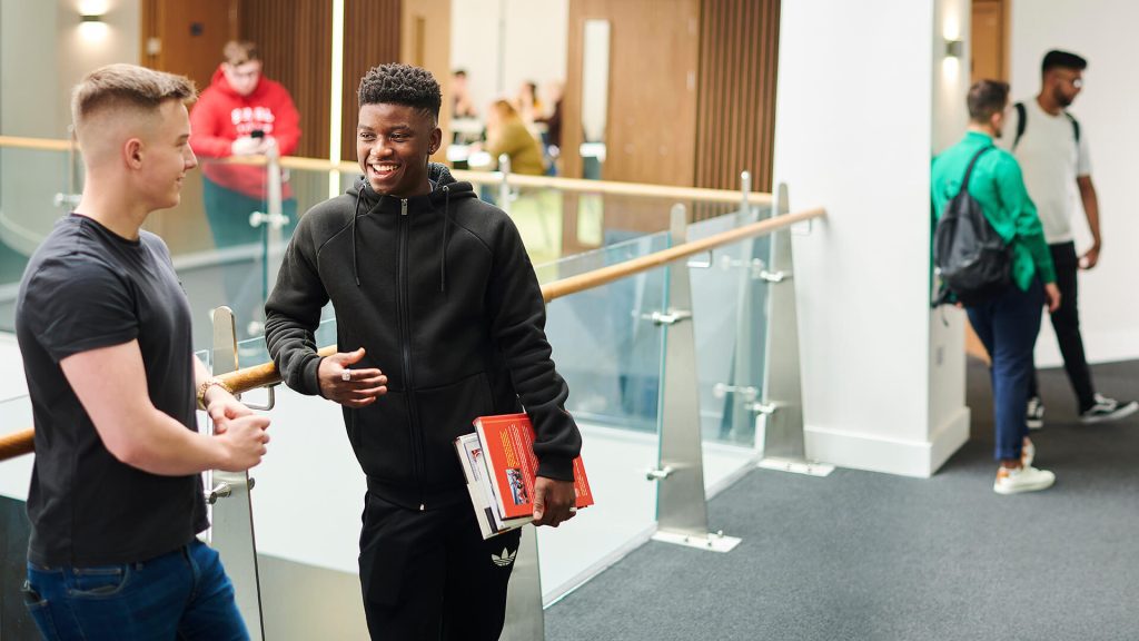 Two students chat while stood in the Law and Psychology building.