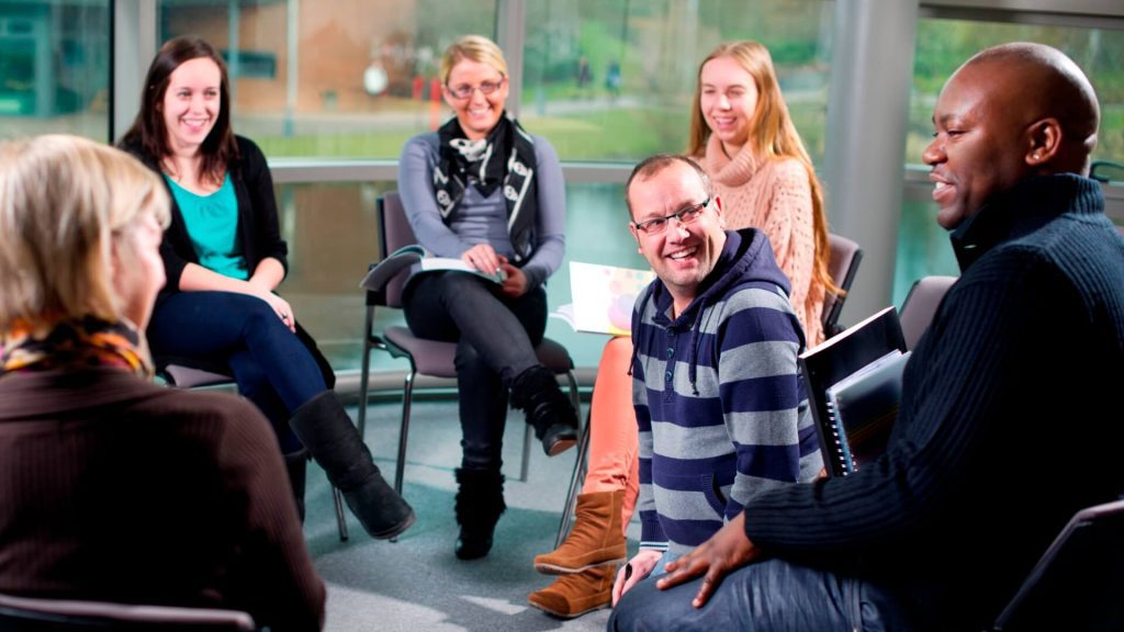 Students sit in a circle around a lecturer while engaging in a group discussion.