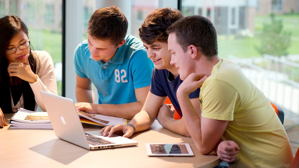 Four students work together round a table in Creative Edge.