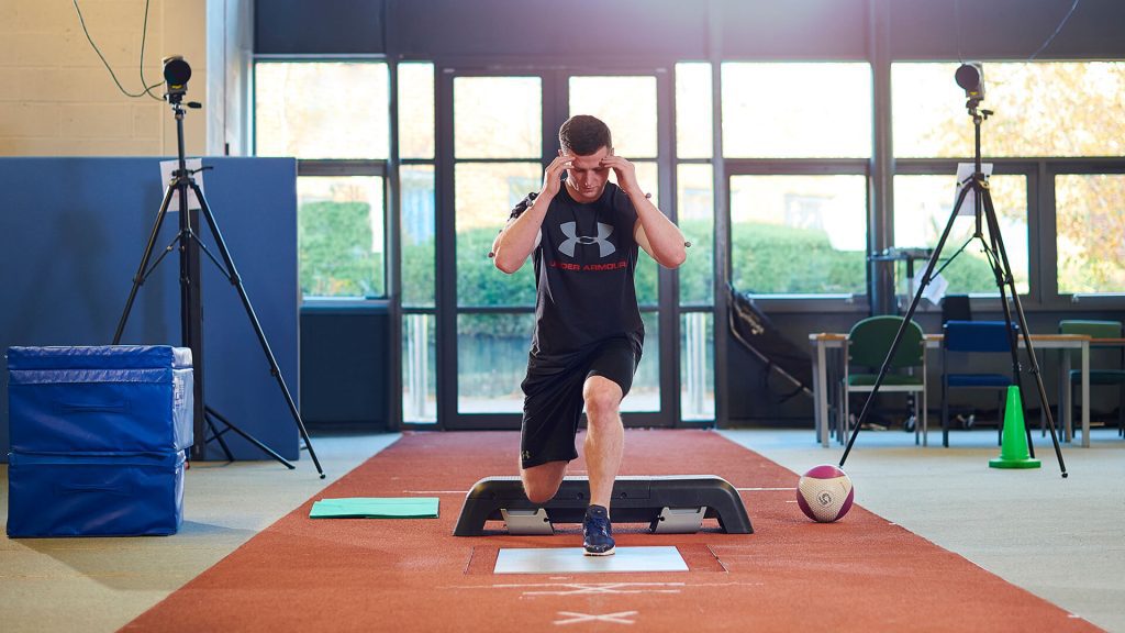 A student crouches down in a sports laboratory.