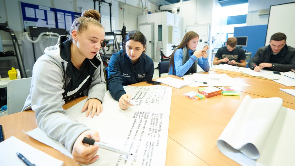 Sport and Exercise Science students make notes on a sheet of A2 paper during a workshop.