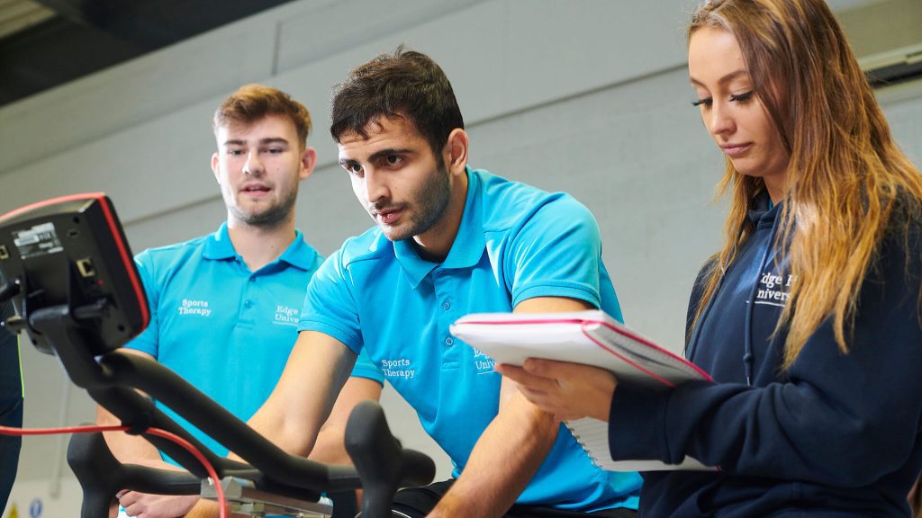 A Sports Therapy student monitors one of their peers as they ride an exercise bike.