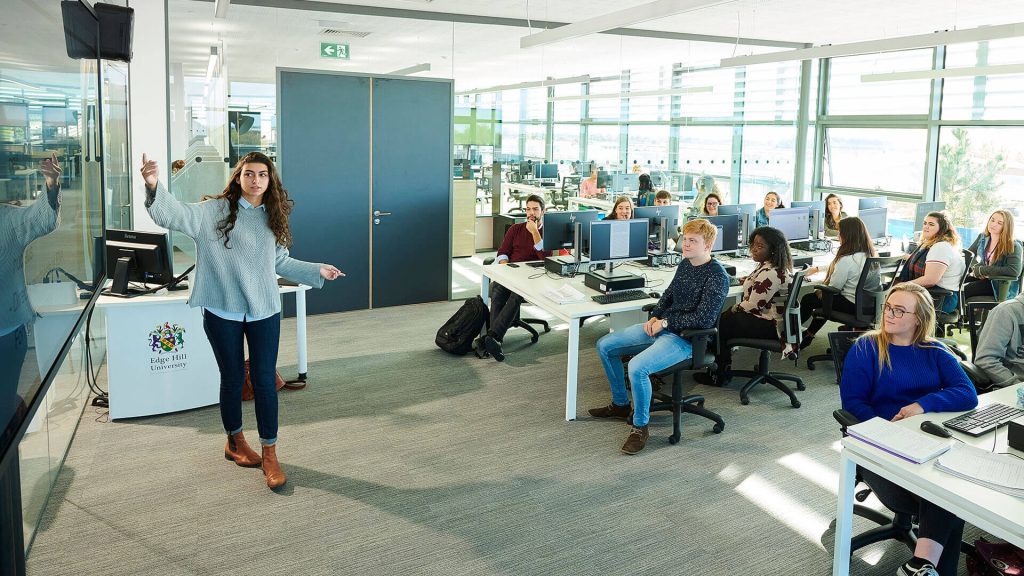 A student gives a presentation to their peers during a seminar in a classroom in the Catalyst building.