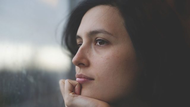 Close up of a woman looking out the window, looking pensive