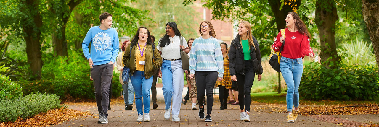 Six students walking through campus laughing together
