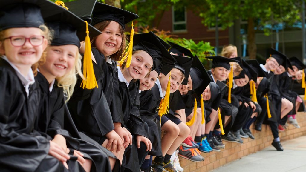 Children in graduation robes smiling at the camera