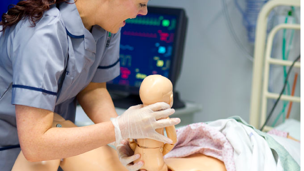 A student nurse is practicing midwifery on a practice mannequin.