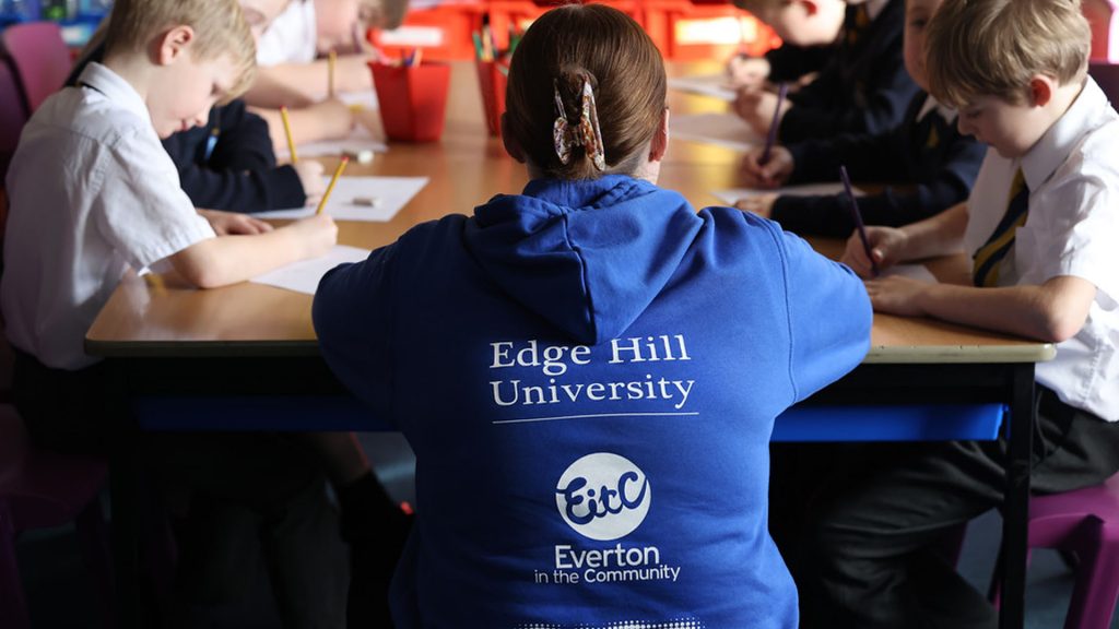 A student wearing an Everton in the Community hoodie whilst working with children