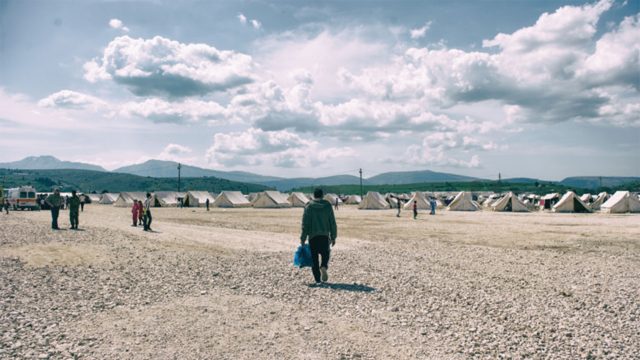 Person walking towards tents at a refugee camp
