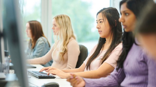 Students in a row looking at computers