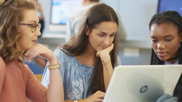 Three students looking at a computer.