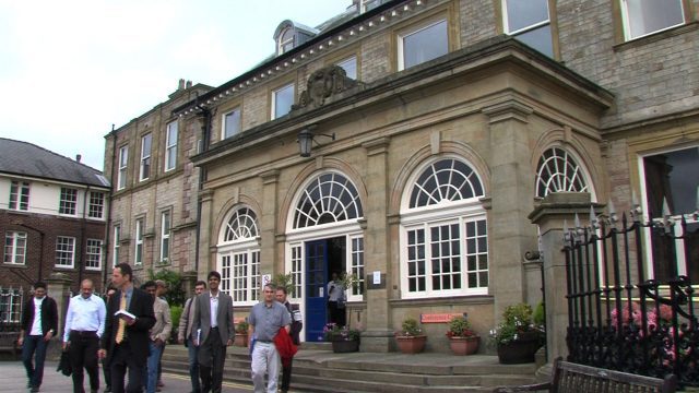 An image of Wrightington Hospital, there is a gathering of people outside all walking away from the hospital doors.