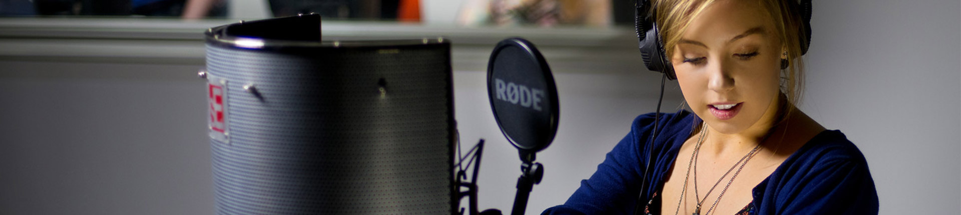 A music production student stands in front of a mic in the recording studio