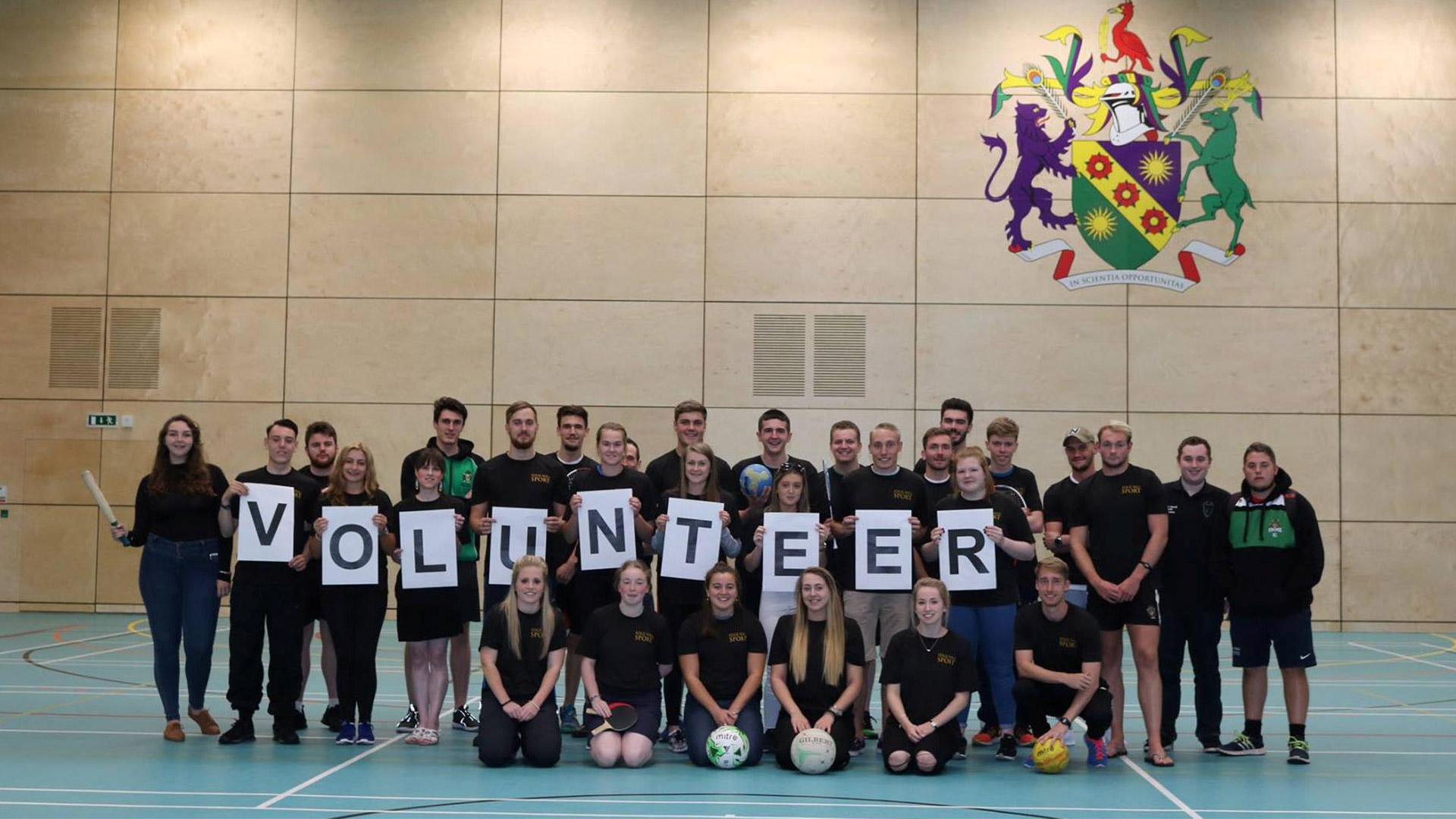 A group of edge hill sport students holding a sign that says volunteer