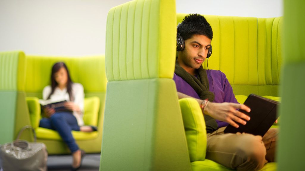 A student sits on a laptop in a booth