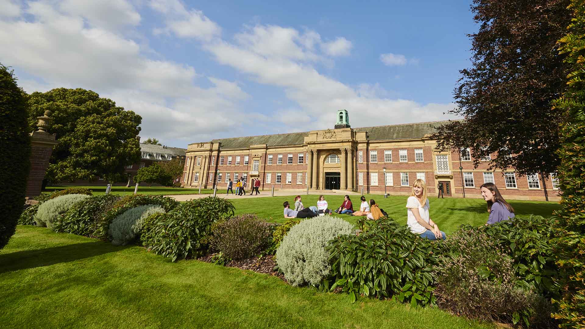 Students sitting on the lawn in front of the main building