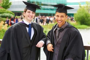 Four graduates, wearing their caps and gowns, on their graduation day.