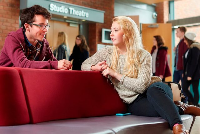 Two students chat in the foyer outside the Studio Theatre in the Performing Arts building.