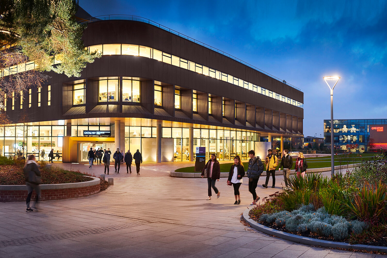 Students walk past the Catalyst building at dusk.