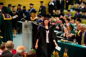 A graduate walks along the red carpet after receiving her award during a graduation ceremony.