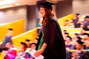 A student prepares to walk along the red carpet and receive her degree.