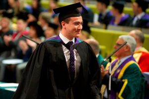 A graduate returns to his seat after his degree has been conferred during a graduation ceremony.