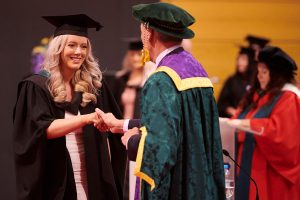 A graduand shakes the hand of Dr John Cater during a graduation ceremony.