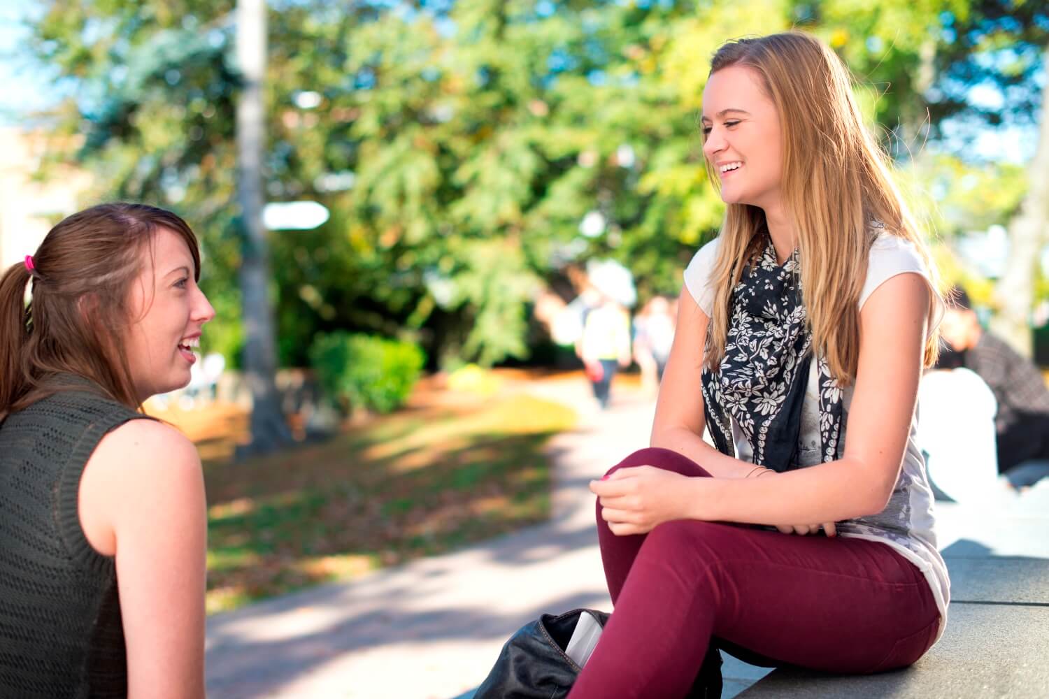 Two students chat while sat by the rear of the Arts Centre overlooking the rose garden on the western side of campus.