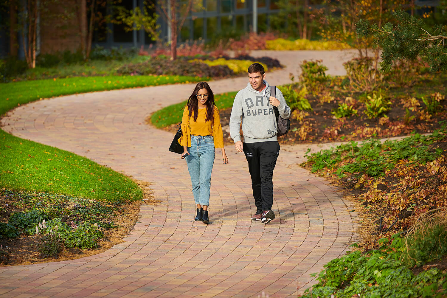 Two students walk on a path between the Wilson Centre and the Catalyst building.