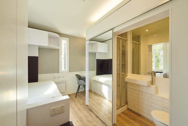 A student bedroom with en-suite bathroom, accessed through a full-length sliding mirror door, in the eastern wing of Main Halls.