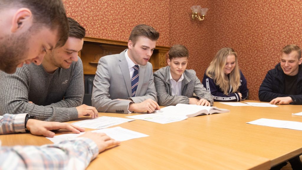 A group of students sat around a table reading documents in the police simulation centre.
