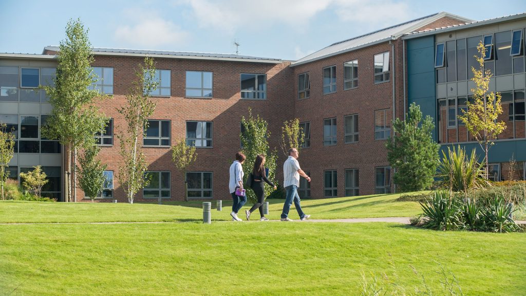An image of a three people walking through the Edge Hill University campus.