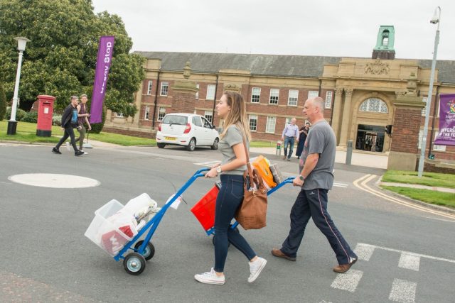 A student and her father push trolleys laden with her belongings.