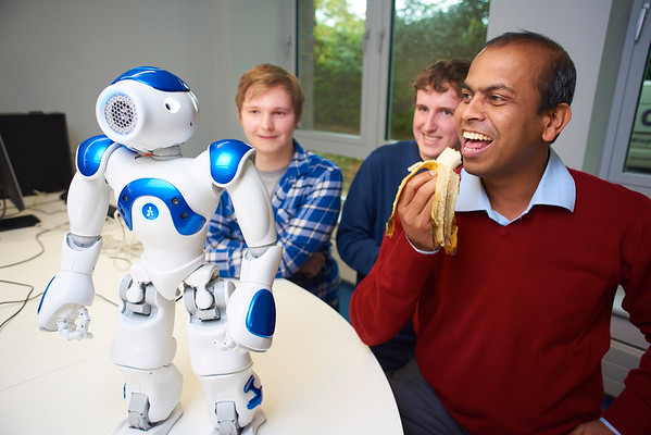 Dr Ardhendu Behera and students smiling and laughing with Robbie the robot