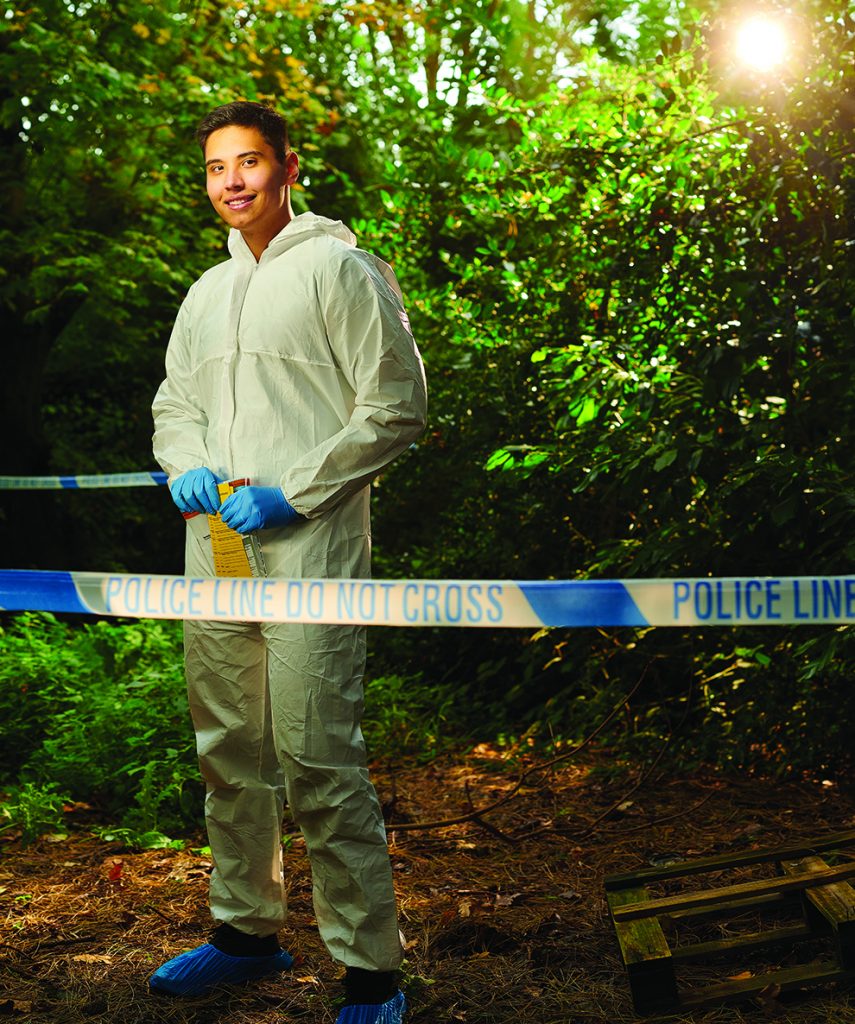 Policing student dressed in forensic over-suit in a simulated crime scene environment.