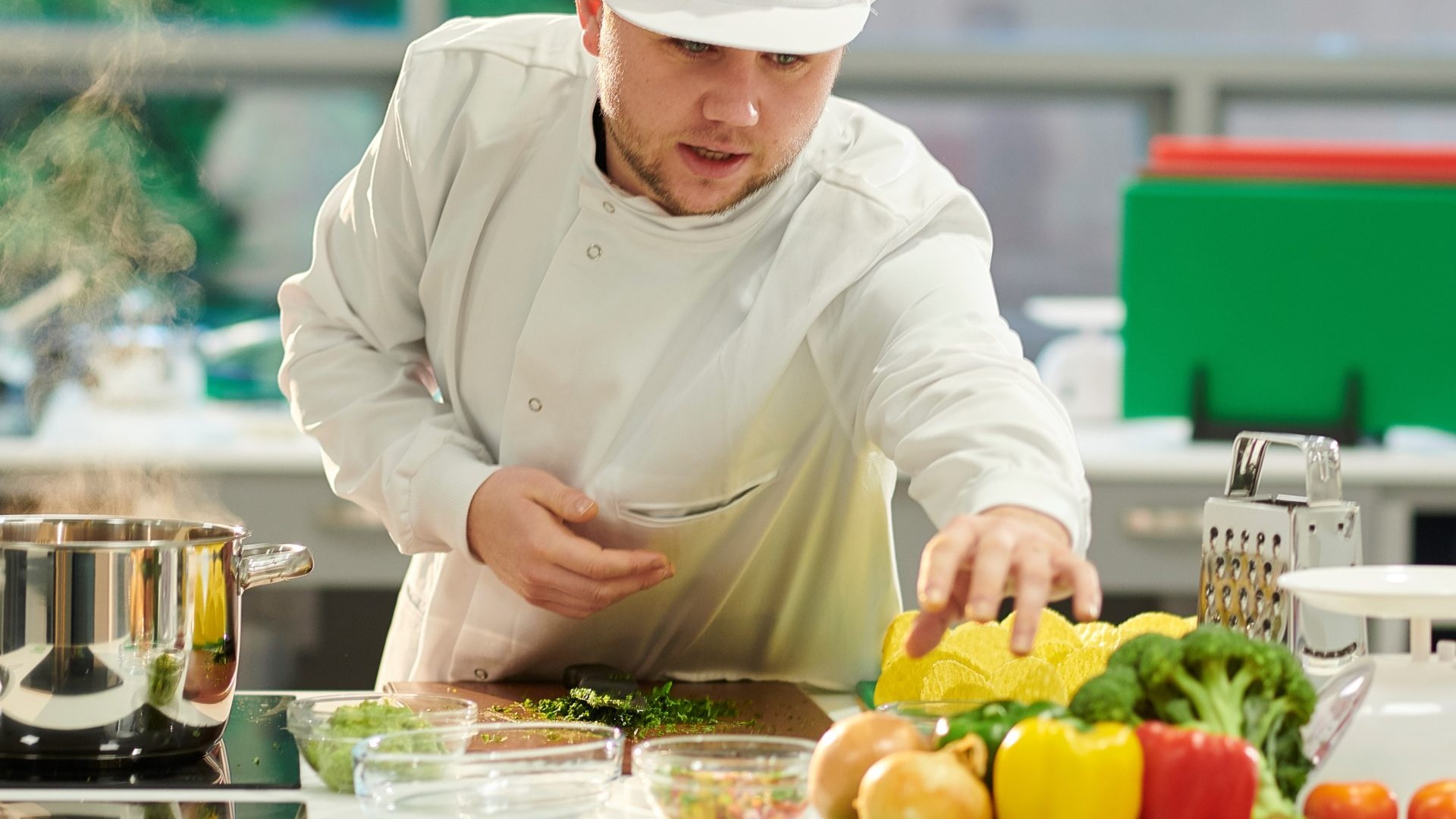 A chef handling and preparing multiple different fruits and vegetables on a counter.