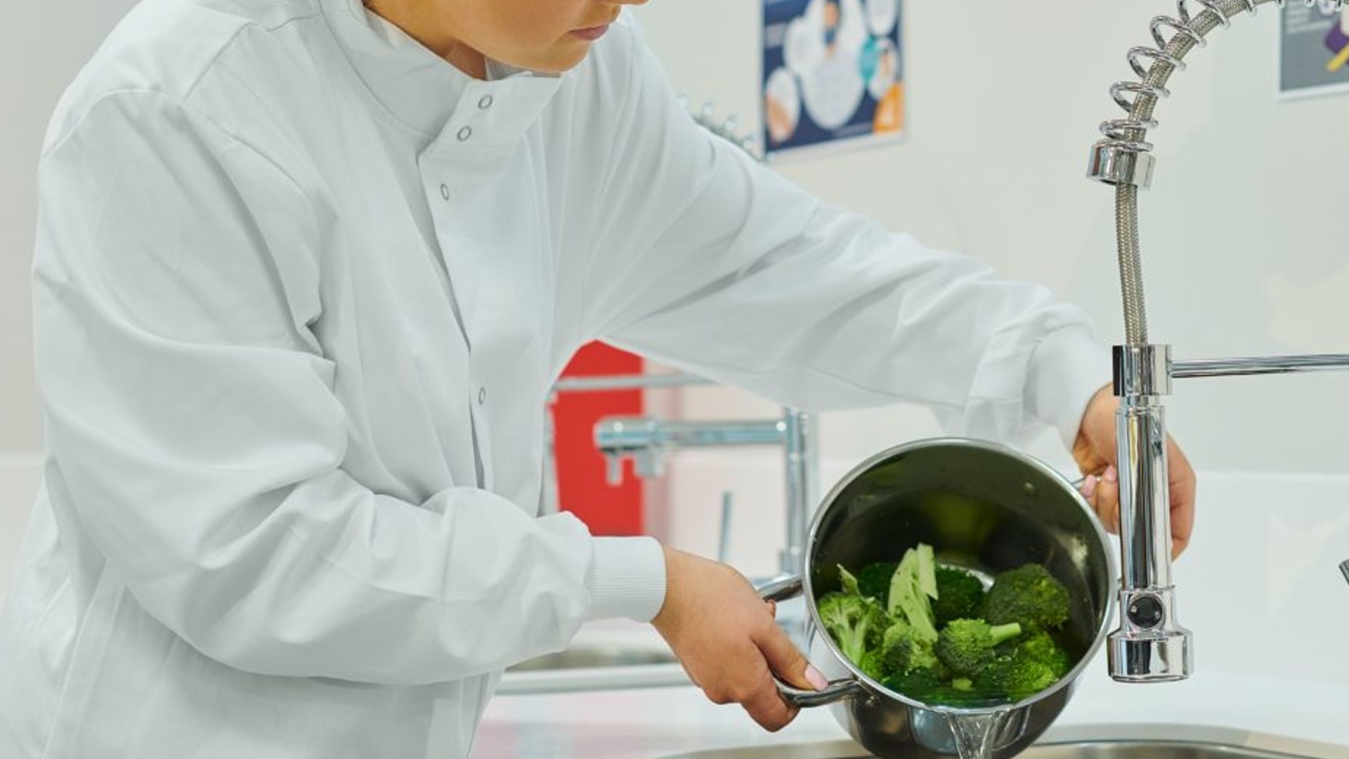 An image of a person washing a pot of vegetables.