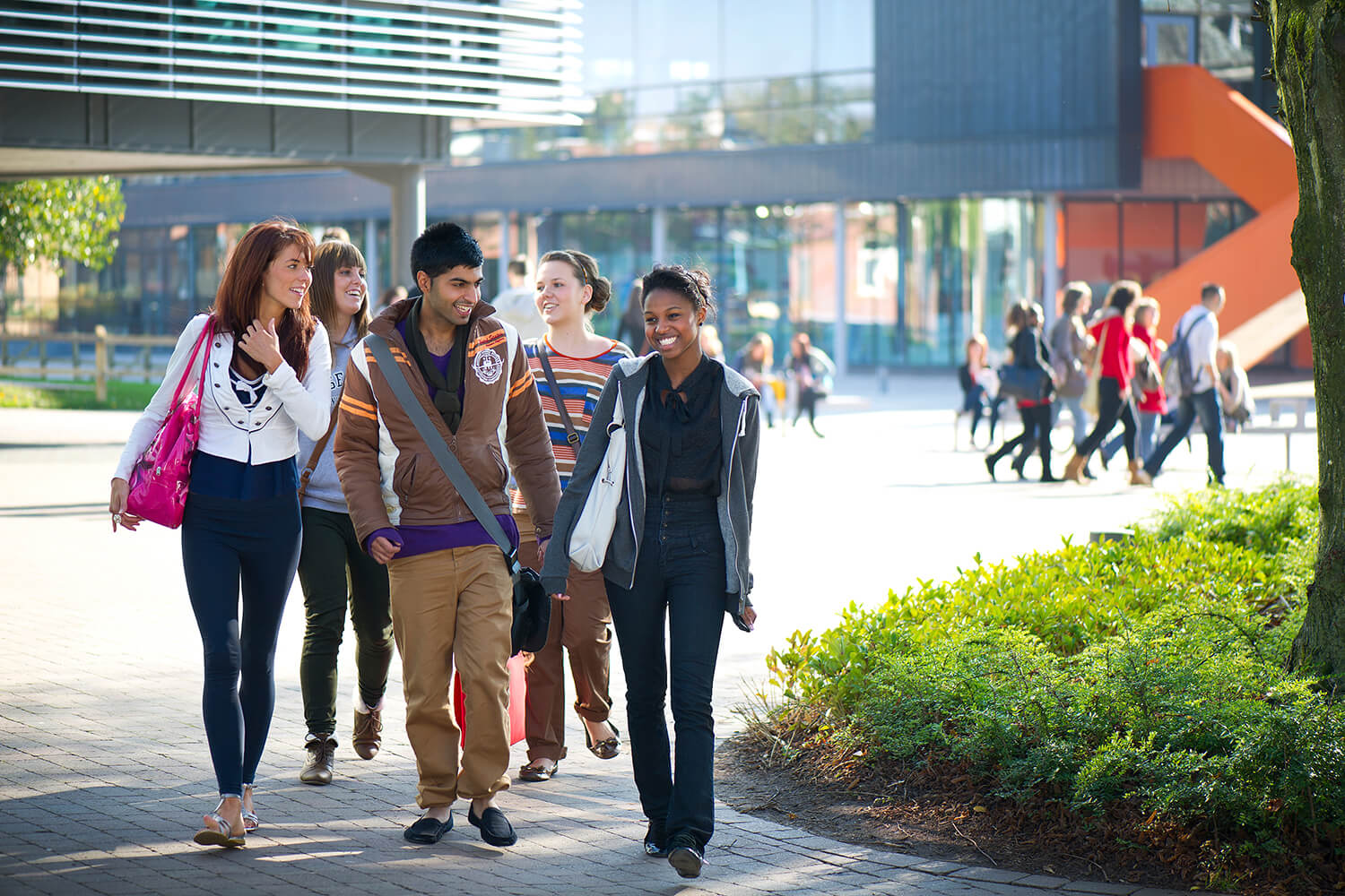 Students walk past the Business School in the centre of the campus, with the Hub visible behind them.