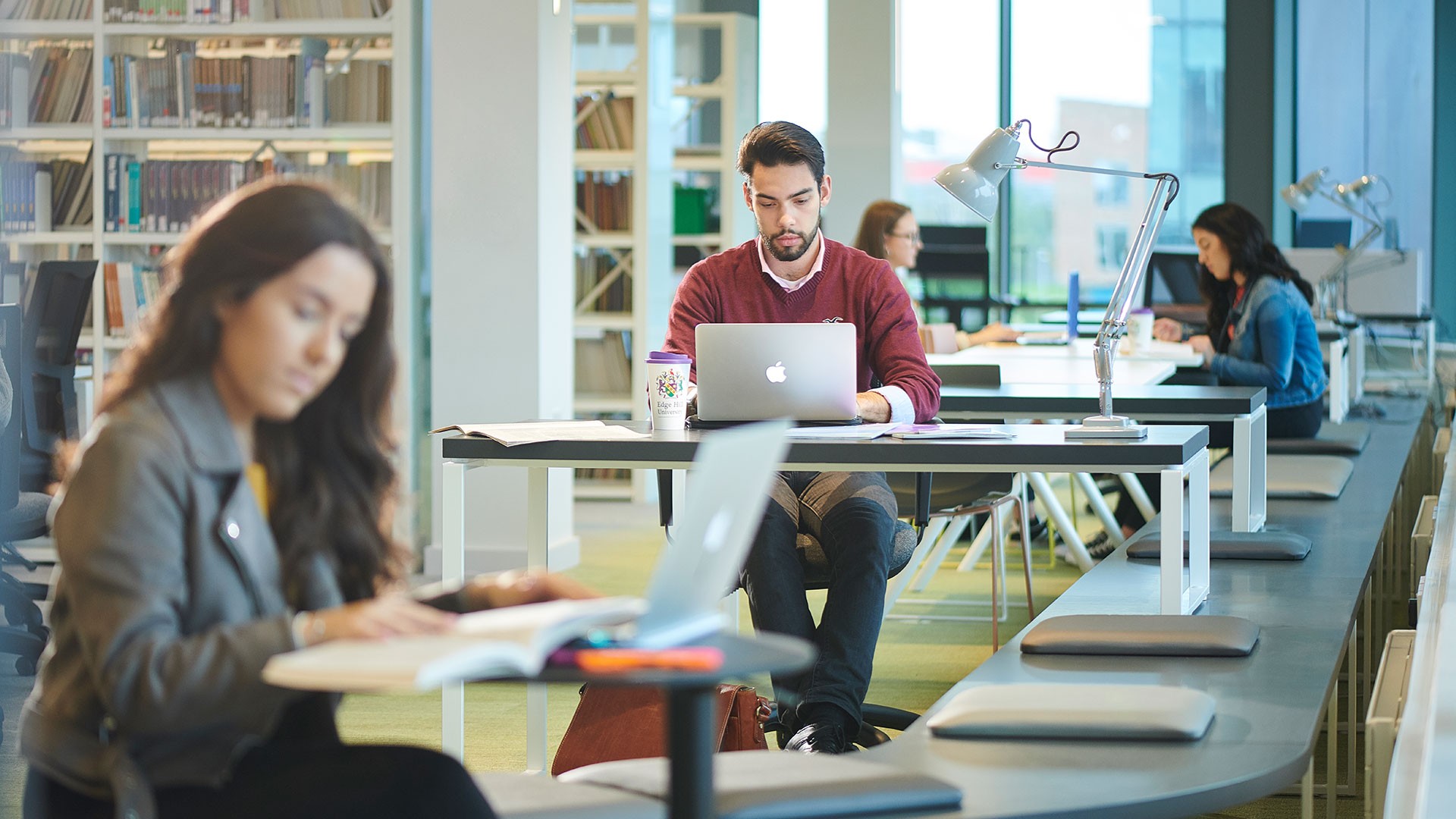 Multiple students are sat at desks in the Edge Hill campus library, Cataylst.