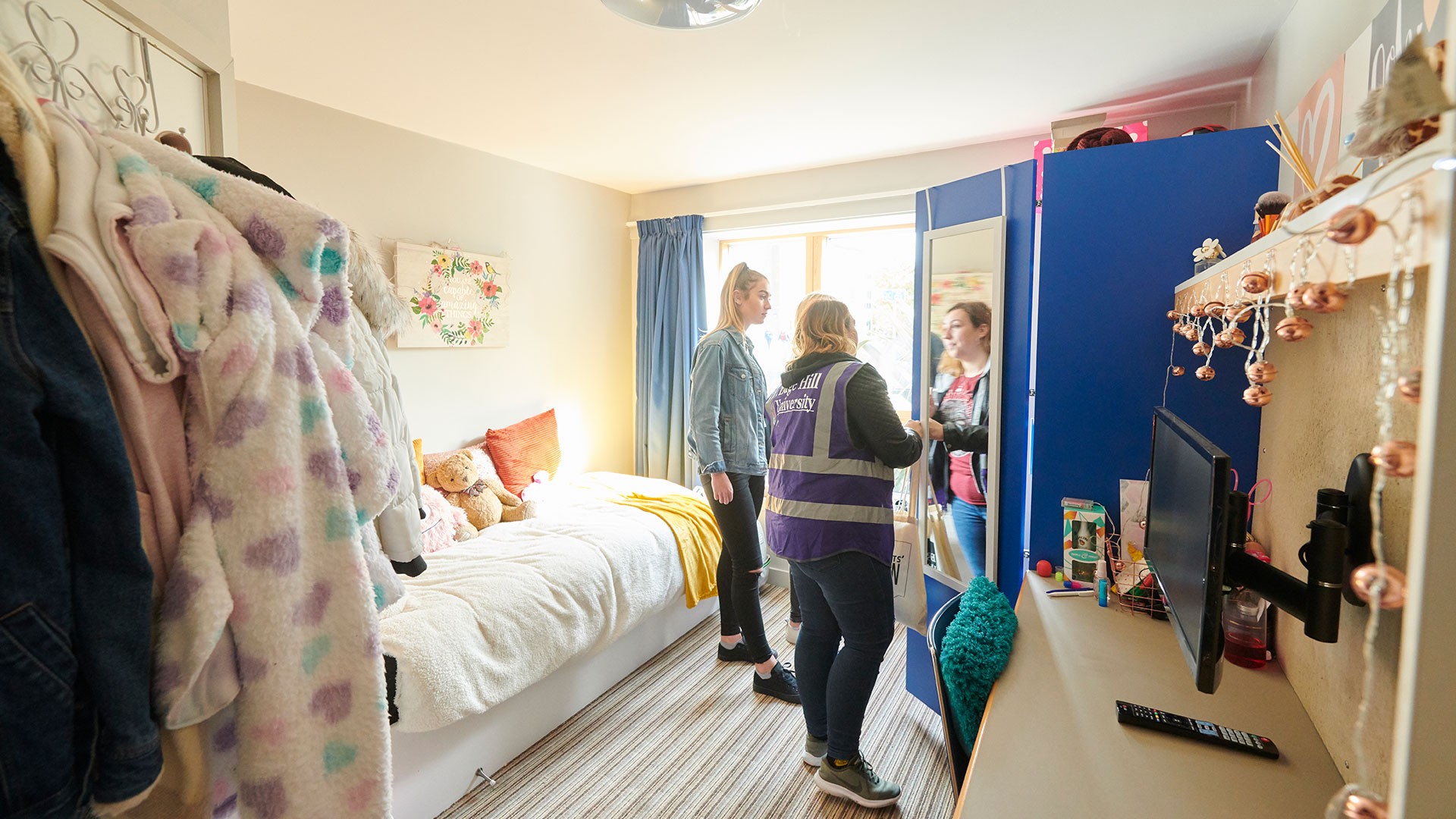 An image of multiple people stood in a furnished room in one of the accommodation blocks at Edge Hill.