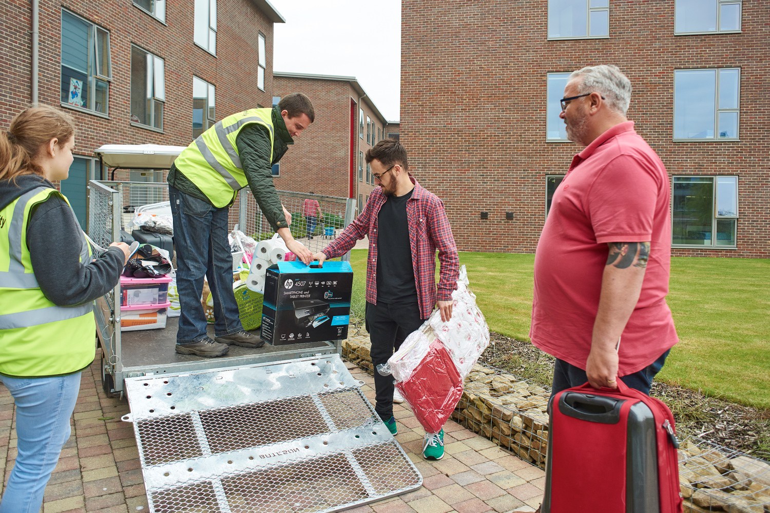 A member of staff assists a student as his possessions are lifted from a trailer.