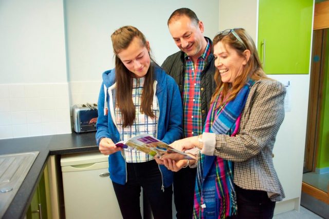 A prospective student and parents looking a printed guide to one of our open days