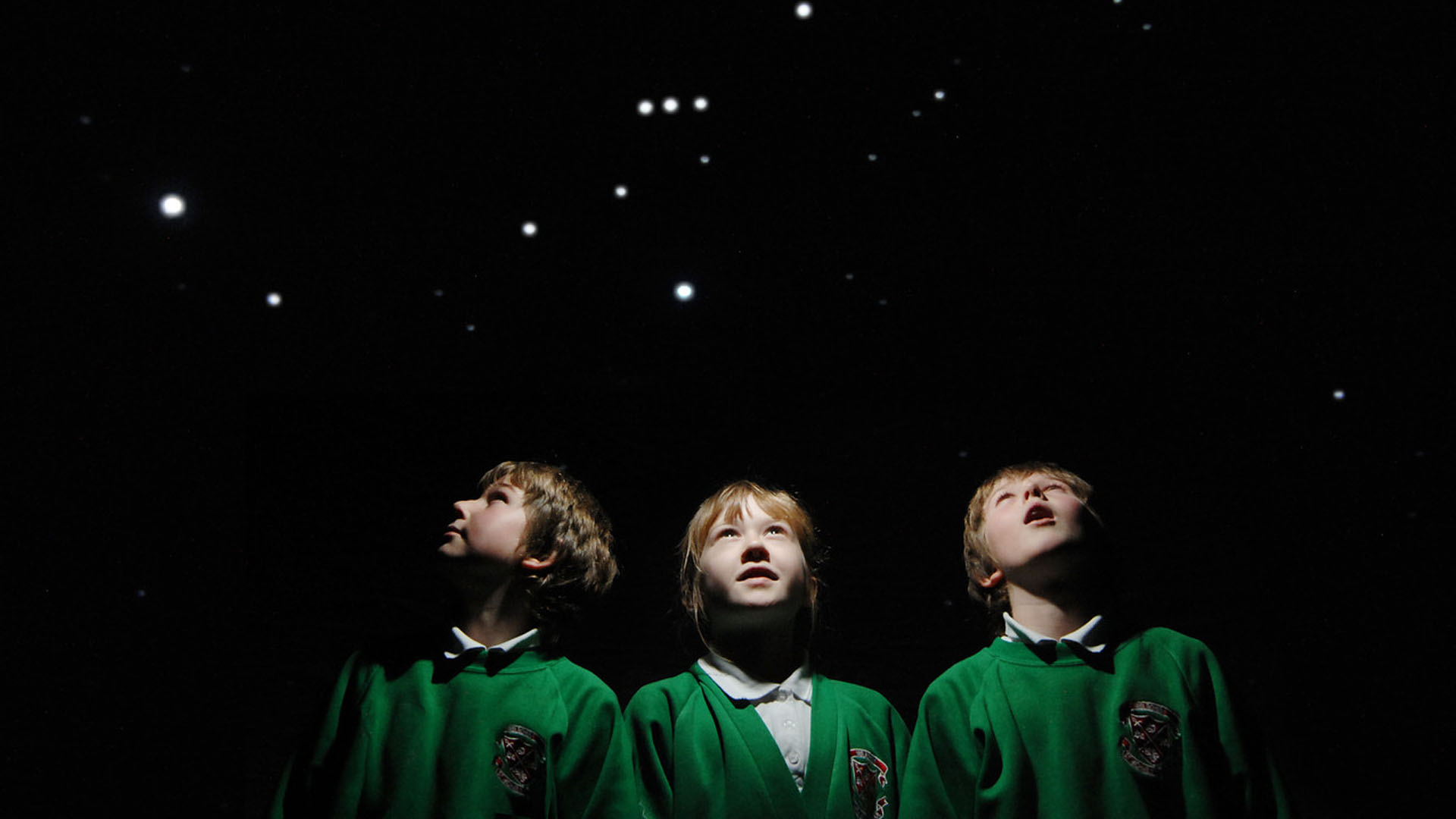 Three primary school children looking at a projection