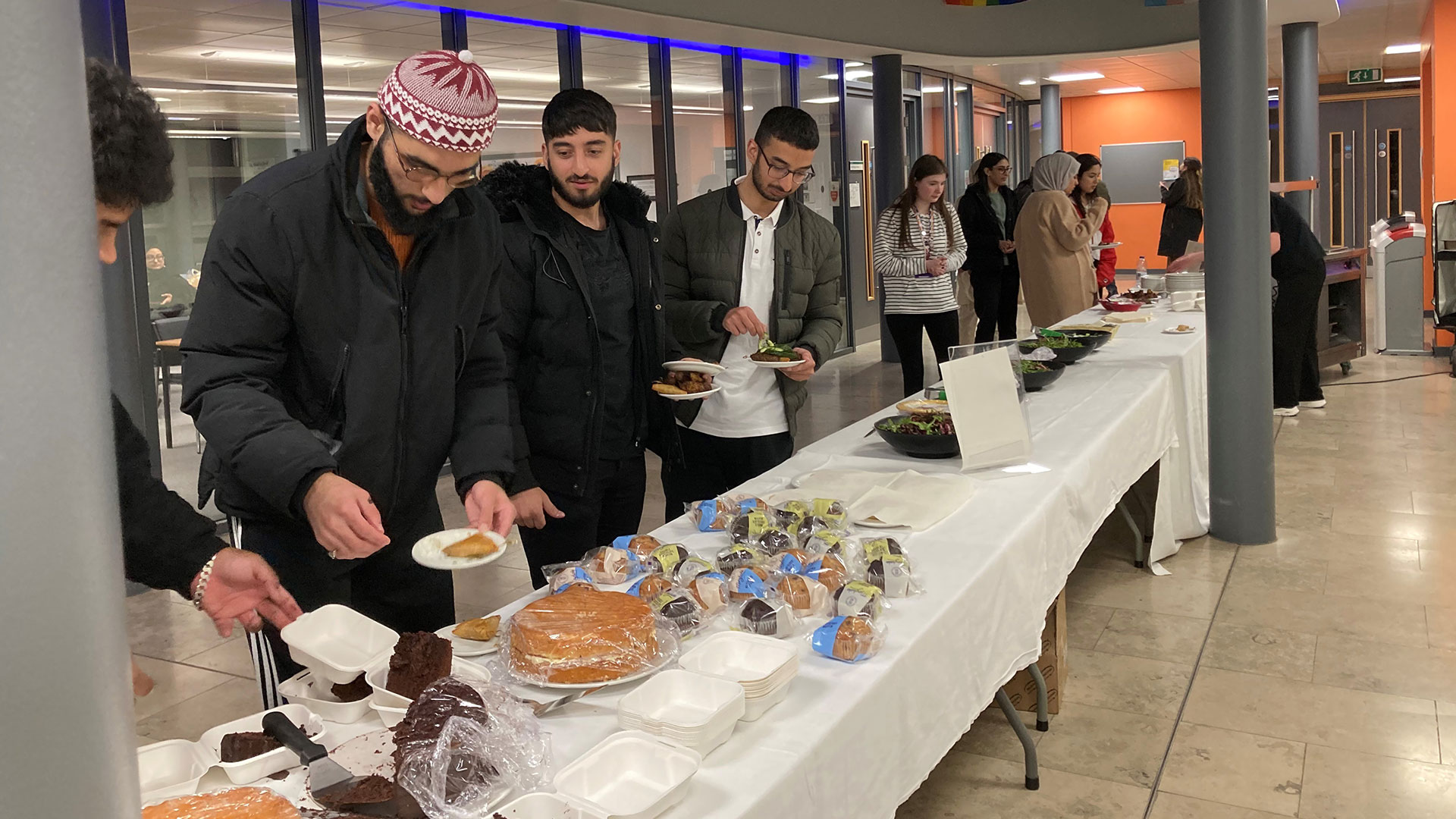 Three Muslim students help themselves to a buffet.