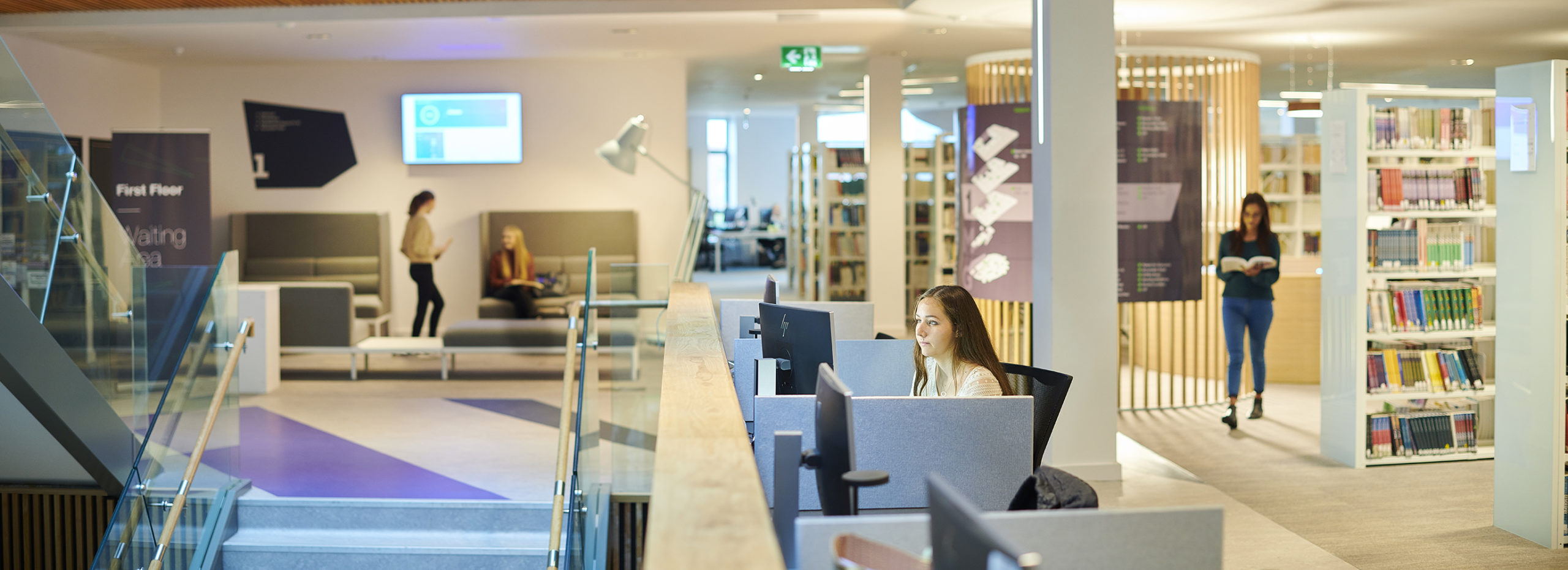 A student works at a computer overlooking a staircase in the Catalyst building.