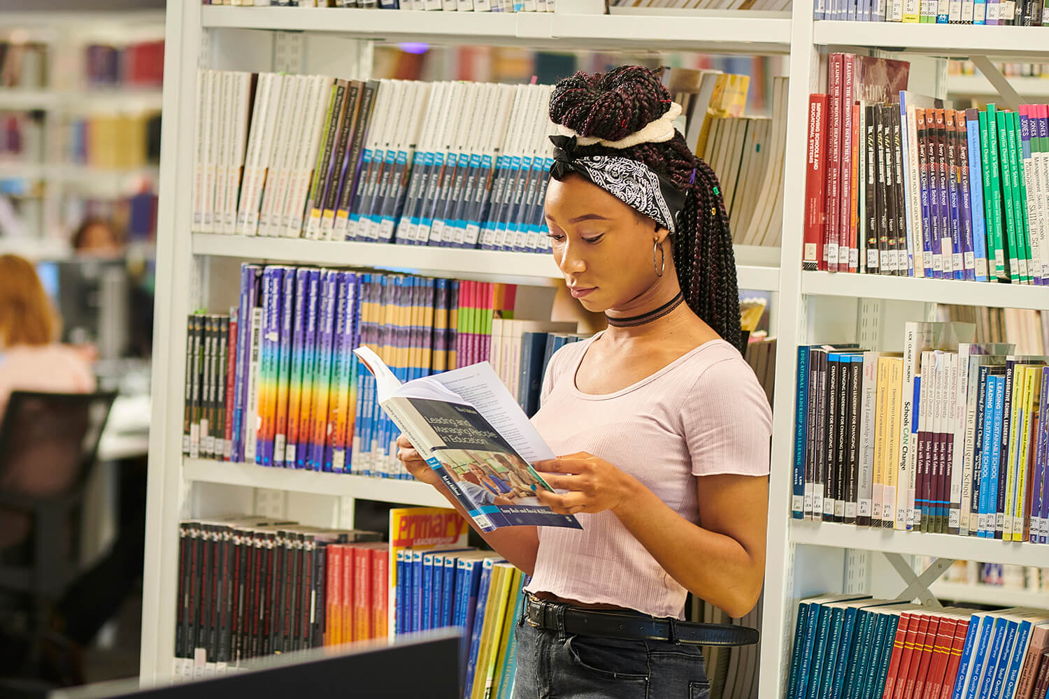 A student browses a book while stood in the University library.