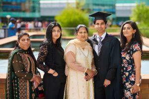 A graduate poses for a photo with his family in the piazza area in the western side of campus.