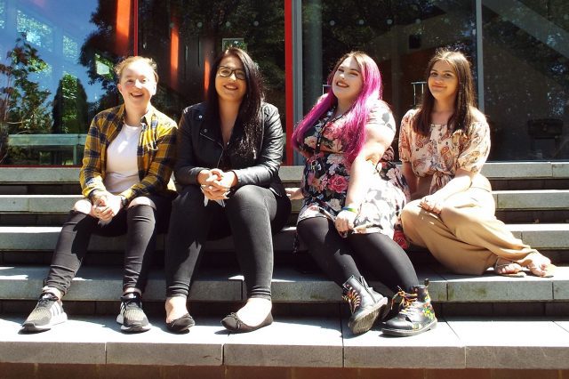 The four elected officers of the Students' Union for academic year 2019/20 sit on the steps at the rear of the Arts Centre.