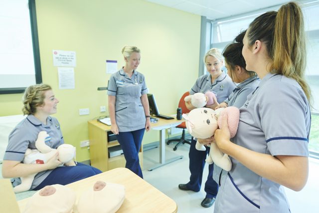 Trainee midwives in their scrubs practice their skills in our clinical simulation suite.