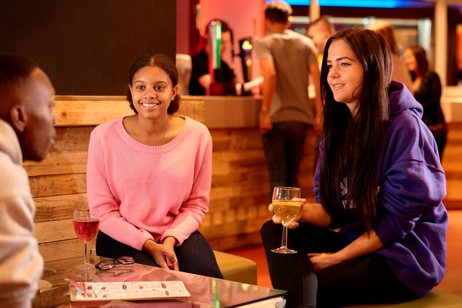 Three students chat over drinks in the SU Bar.